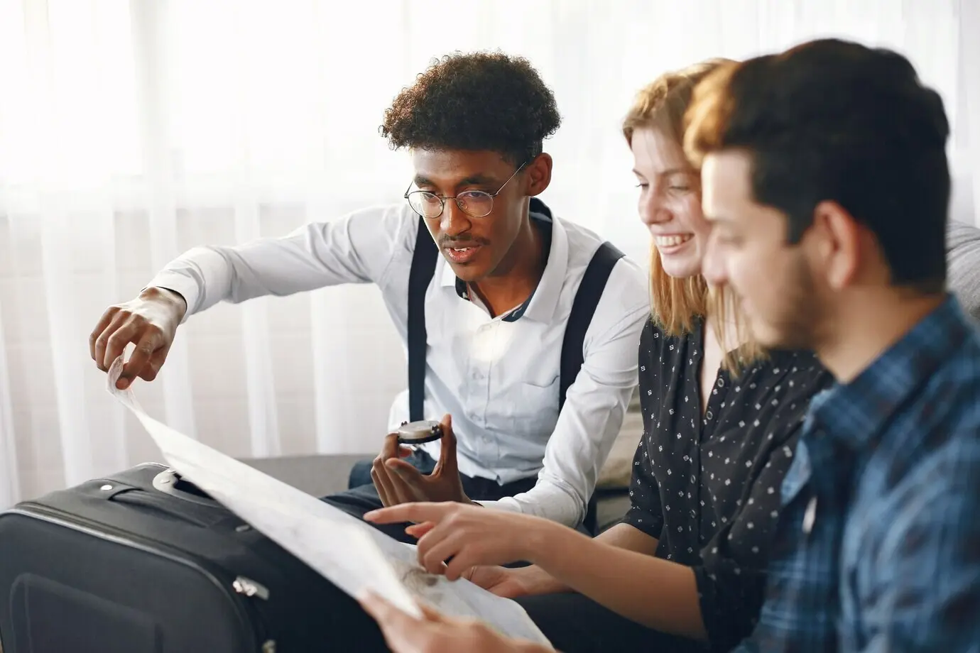 Счастливая компания друзей планирует поездку. Путешественники по миру изучают карту, находясь дома. Европейская и индийская этническая принадлежность.